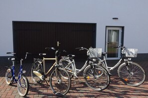 A row of bicycles parked in front of a building with a large garage door and a door with a window. - Holiday home with 1 bedroom (Unterspreewald)