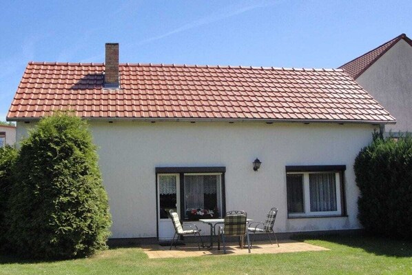 A single-story house with a red-tiled roof, a chimney, and a patio with outdoor furniture. - Holiday home with 1 bedroom (Unterspreewald)