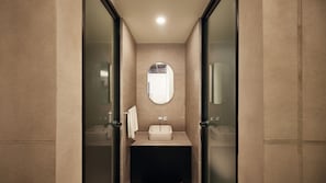 Un bany modern amb un separador de vidre, un lavabo al centre i un mirall a sobre.