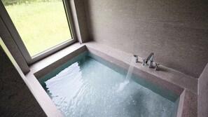 Una bañera con un grifo y una ventana encima.