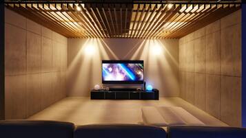 A modern cinema room with a flat-screen TV, wooden slats overhead, and a cushioned seating area.