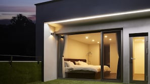Un dormitori modern amb llit, una tauleta de nit i una finestra amb cortines.