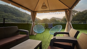 Un espace extérieur aménagé avec des meubles en osier et offrant une vue sur un paysage verdoyant et luxuriant.