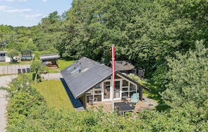Et hus med terrasse, omgivet af frodig vegetation.