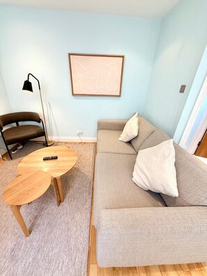 A living room with a sofa, a round coffee table, a floor lamp, and a framed abstract artwork on the wall. - Flat 4 Beautiful Central London Apartment (London)