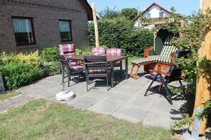 A patio with a table and chairs, surrounded by greenery and a brick building. - Holiday home in Ludorf with swimming pool (Ludorf)