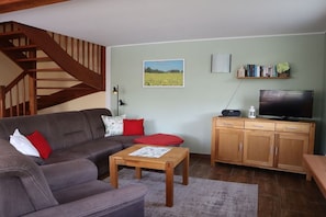 A living room with a sofa, a coffee table, a TV, and a bookshelf. - Holiday home in Ludorf with swimming pool (Ludorf)