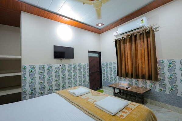 Habitación de hotel con una cama, televisor, aire acondicionado y una ventana con cortinas.