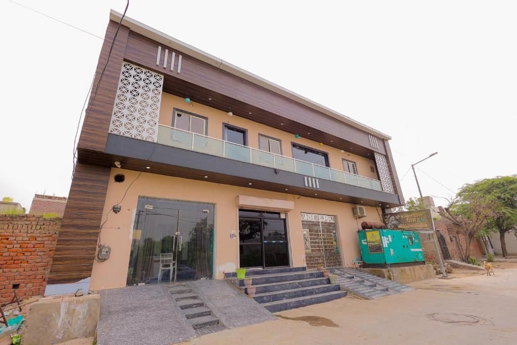 Un edificio de dos pisos con techo plano, un balcón en el nivel superior y una escalera que lleva a la entrada.