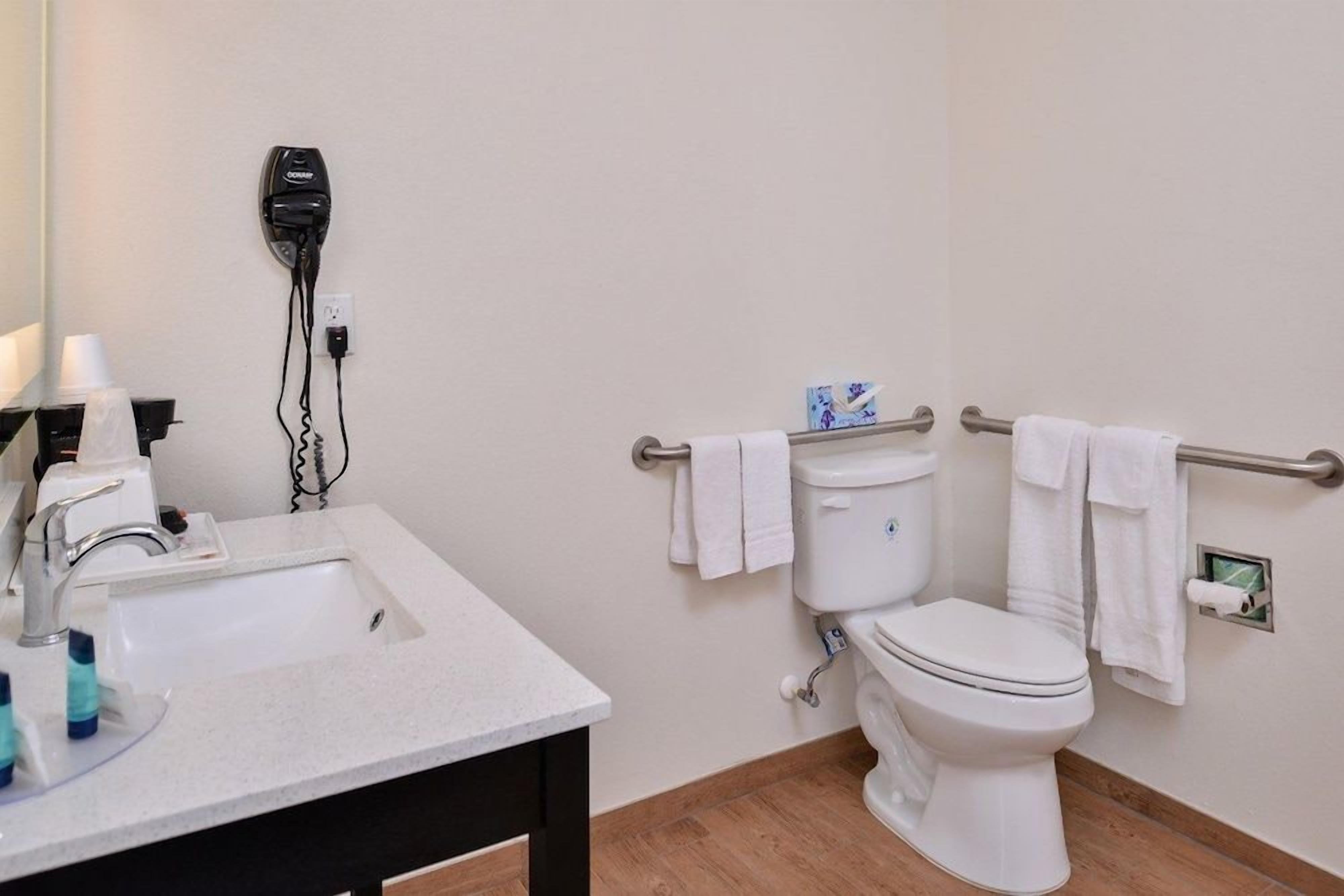 A bathroom with a sink, toilet, and hand dryer.