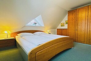 Ein Schlafzimmer mit einem Holzbett, zwei Nachttischlampen, einem Kleiderschrank und einem Oberlicht.