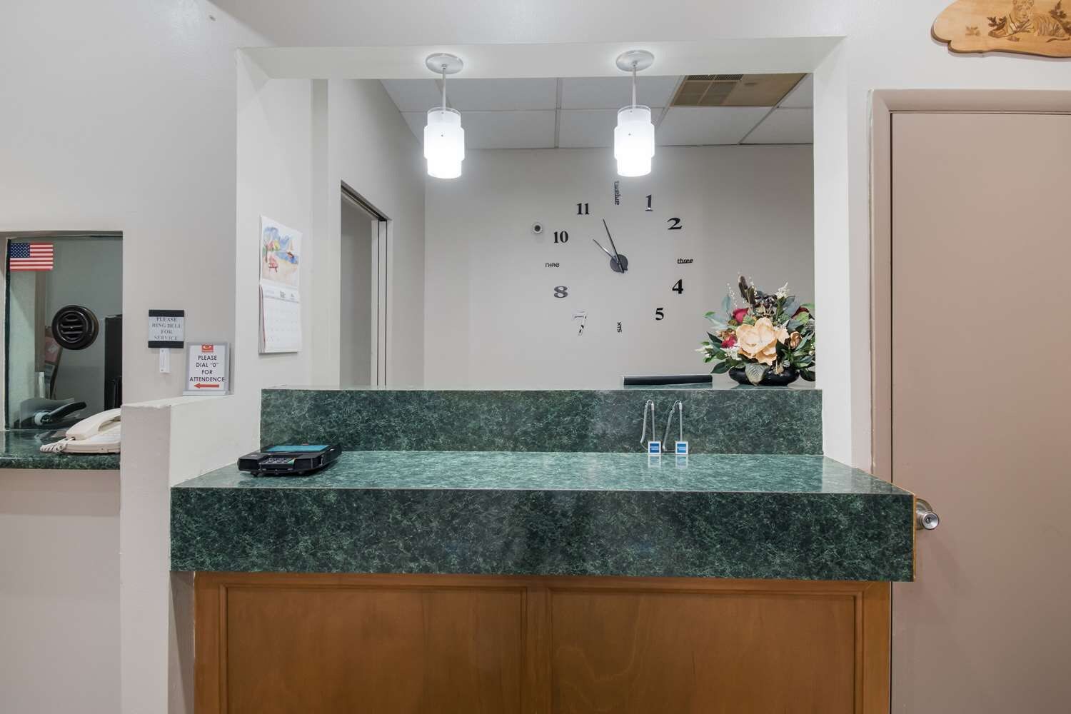 A reception desk with a clock, a phone, and a vase of flowers.