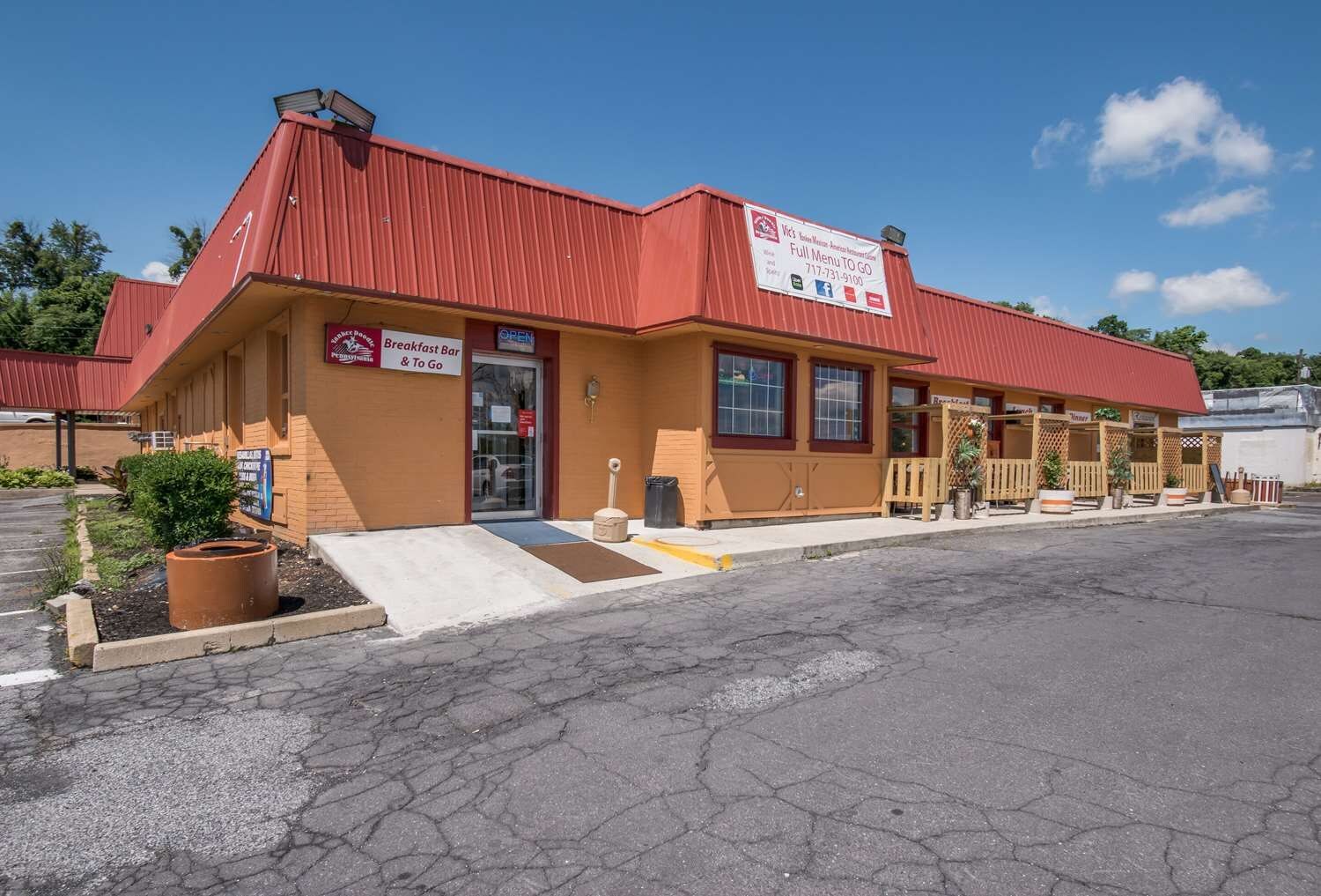 A standalone building with a red roof and a sign indicating a breakfast bar and to-go options.