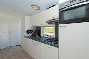 Eine kompakte Küche mit Backofen, Kaffeemaschine und Fenster mit Blick ins Freie.