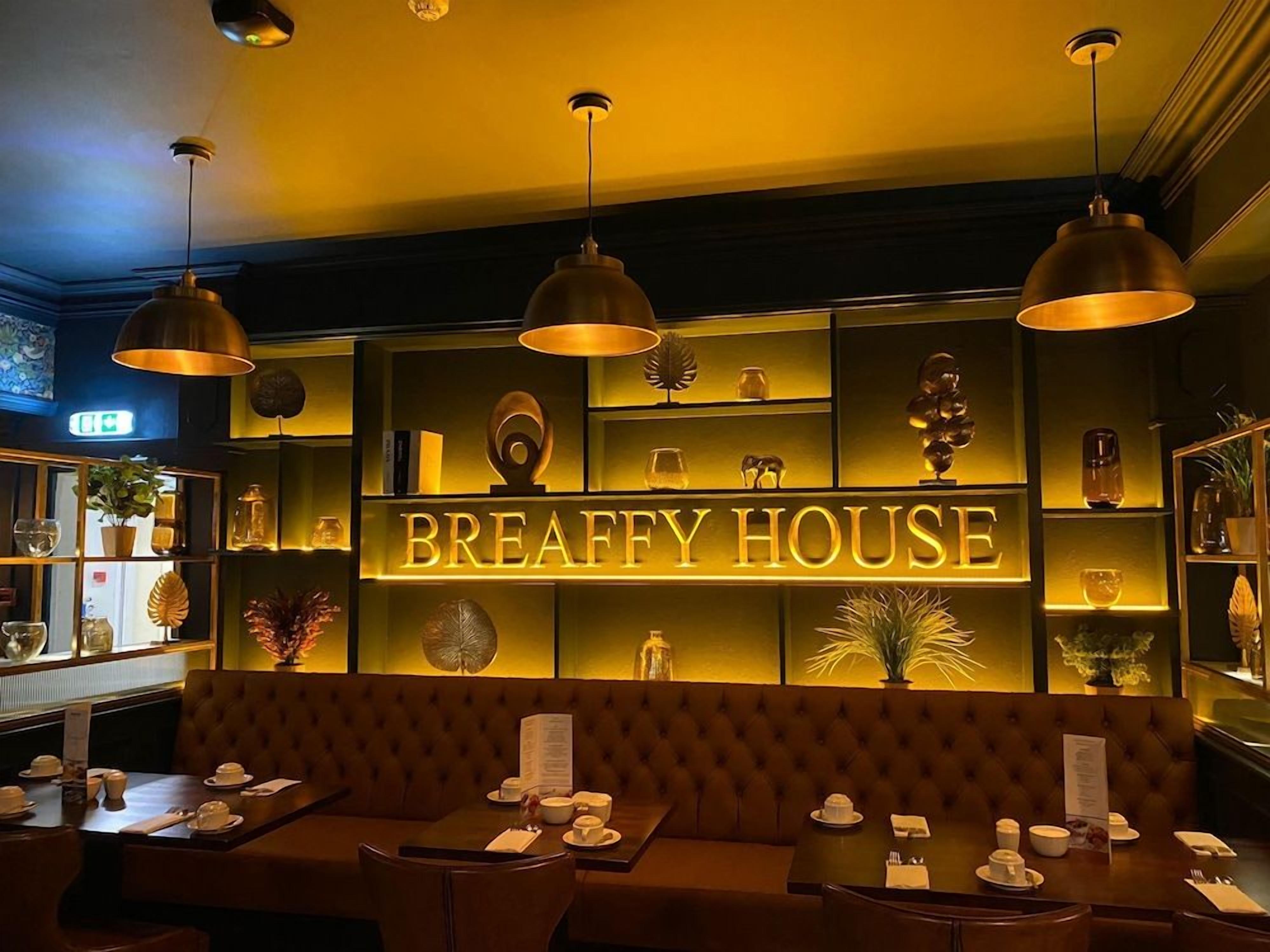 A restaurant interior with a sign reading 'BREAFFY HOUSE' and a seating area with tables set for dining.
