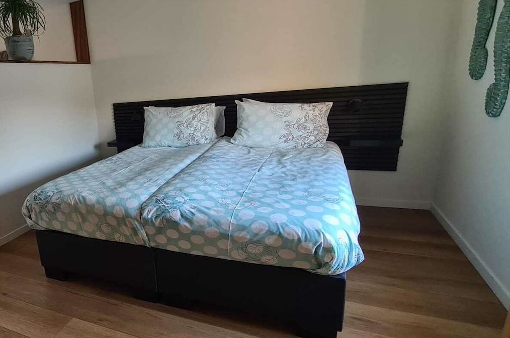 A bed with a dark headboard and a patterned bedspread.