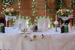 A table set for a wedding reception with floral centerpieces, glasses, and bottles. - Bona (Kraków)