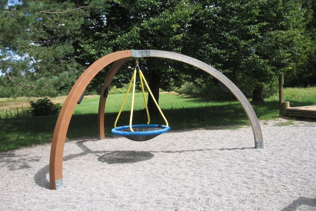 Eine Schaukelanlage im Park mit einer Metallbogenkonstruktion und einem blauen Schaukelstuhl.
