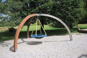 Eine Schaukelanlage im Park mit einer Metallbogenkonstruktion und einem blauen Schaukelstuhl.