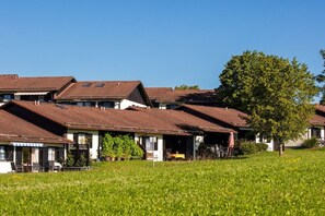 Eine Reihe Häuser mit geneigten Dächern und einem grünen Rasen im Vordergrund.
