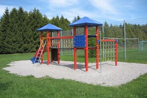 Ein Spielplatz mit Klettergerüst, Rutschen und einem Netzbereich.
