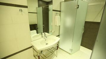 A bathroom with a sink, mirror, and a glass shower enclosure.