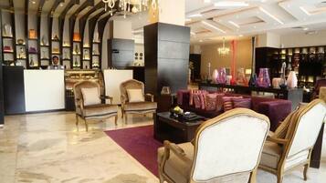 A hotel lobby with a reception desk, seating area, and a display of decorative items.