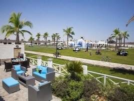 Un área de estar al aire libre con mobiliario de mimbre y vistas a un campo de golf.