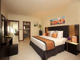 Una habitación de hotel con una cama grande, mesitas de noche, un escritorio y un espejo.