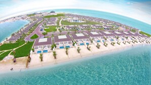 En semesteranläggning vid kusten med flera hotellbyggnader, simbassänger och en strand.