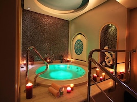 Área de spa com hidromassagem, velas e um painel decorativo.