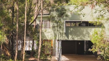 A building with a green exterior, a garage door, and a pathway leading to the entrance.
