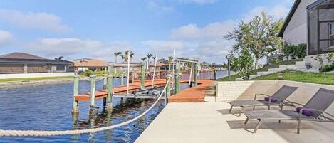 A swimming pool with a bridge, lounge chairs, and a modern building.