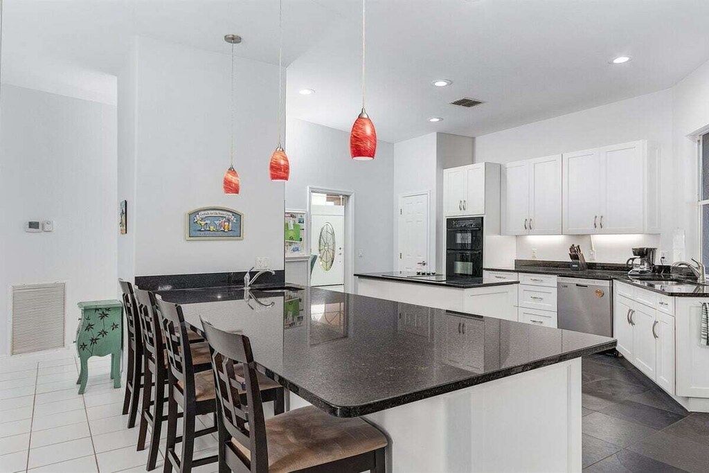 A modern kitchen with a central island, white cabinetry, and pendant lighting. - Villa in Cape Coral, with swimming pool (Cape Coral,)