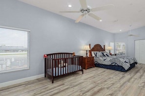 A bedroom with a crib, a bed, a nightstand, and a ceiling fan. - Villa in Cape Coral, with swimming pool (Cape Coral,)