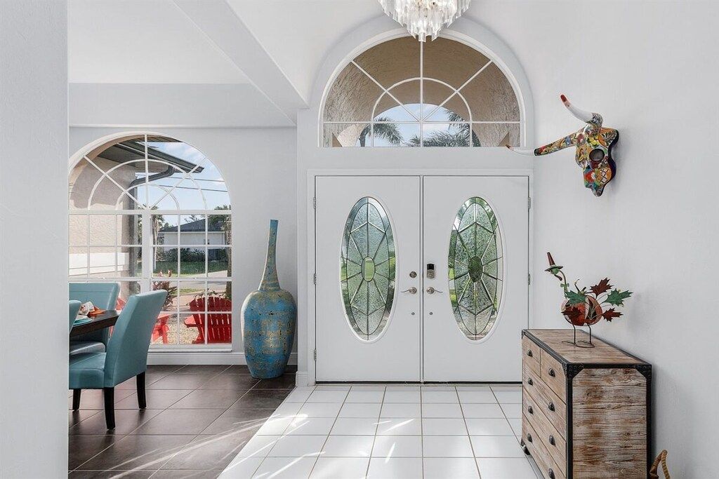 Una habitación con una puerta blanca, un jarrón azul y un mueble de madera con un objeto decorativo.