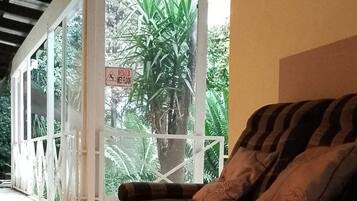 A room with a sofa, a butterfly decoration, and a view of greenery outside.
