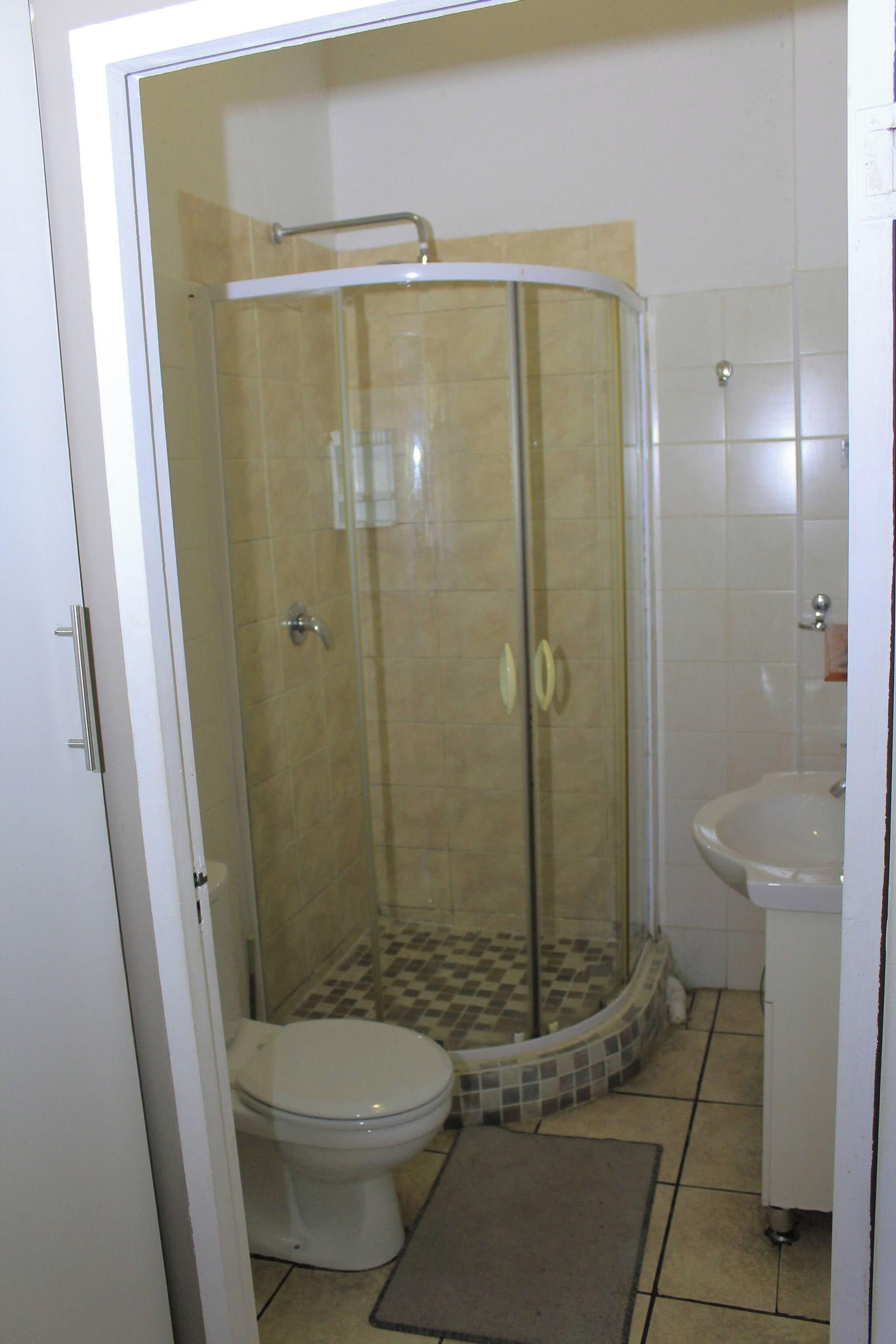 A bathroom with a glass-enclosed shower, a toilet, and a sink.