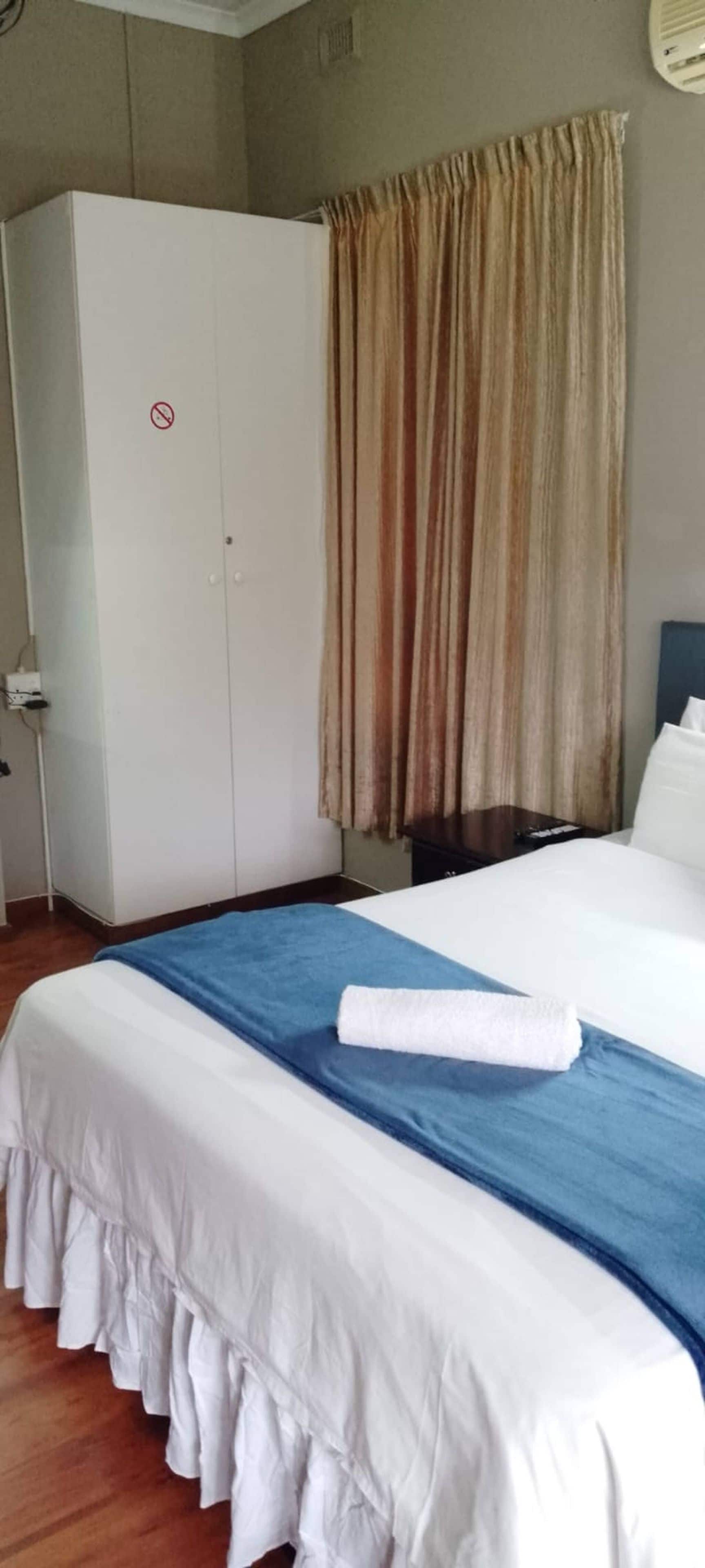 Ein Hotelzimmer mit einem Bett, einem Kleiderschrank und einem Vorhang.