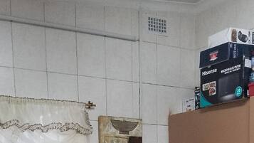 Une cuisine avec des murs recouverts de carreaux blancs, un four à micro-ondes, un grille-pain et un évier.