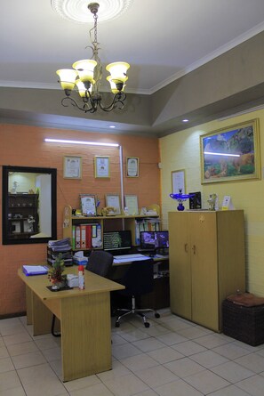 An office with a desk, computer, and a chandelier.