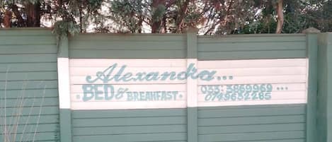 A green gate with a sign for 'Alexandra Bed & Breakfast' including a phone number.