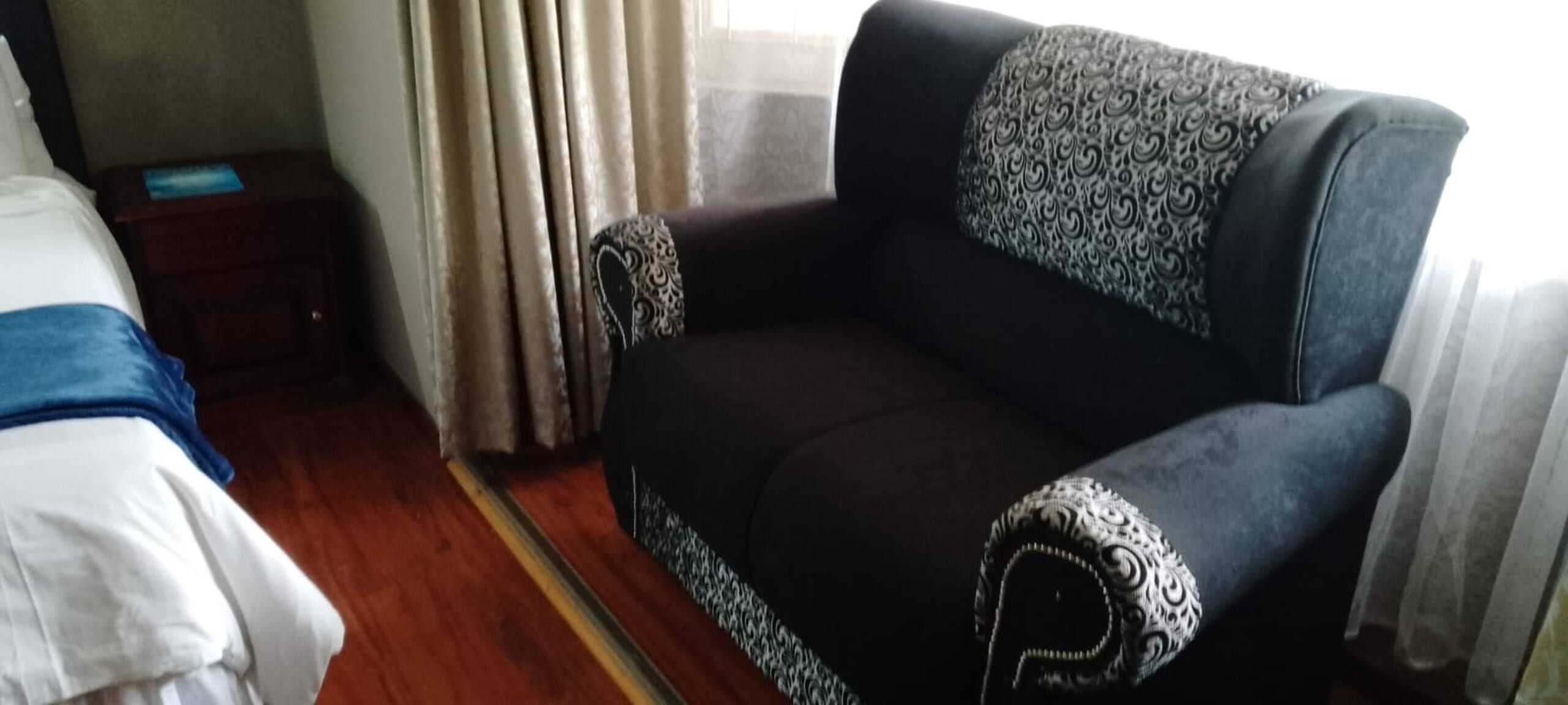 Una stanza con un letto, un divano e un comodino.