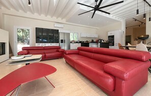 Un salon moderne avec un canapé d’angle rouge, une table à manger rouge et une cuisine en arrière-plan.