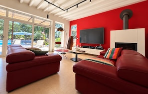 A modern living room with red sofas, a flat-screen TV, and a fireplace. - Maison piscine au calme (Méjannes-Le-Clap)