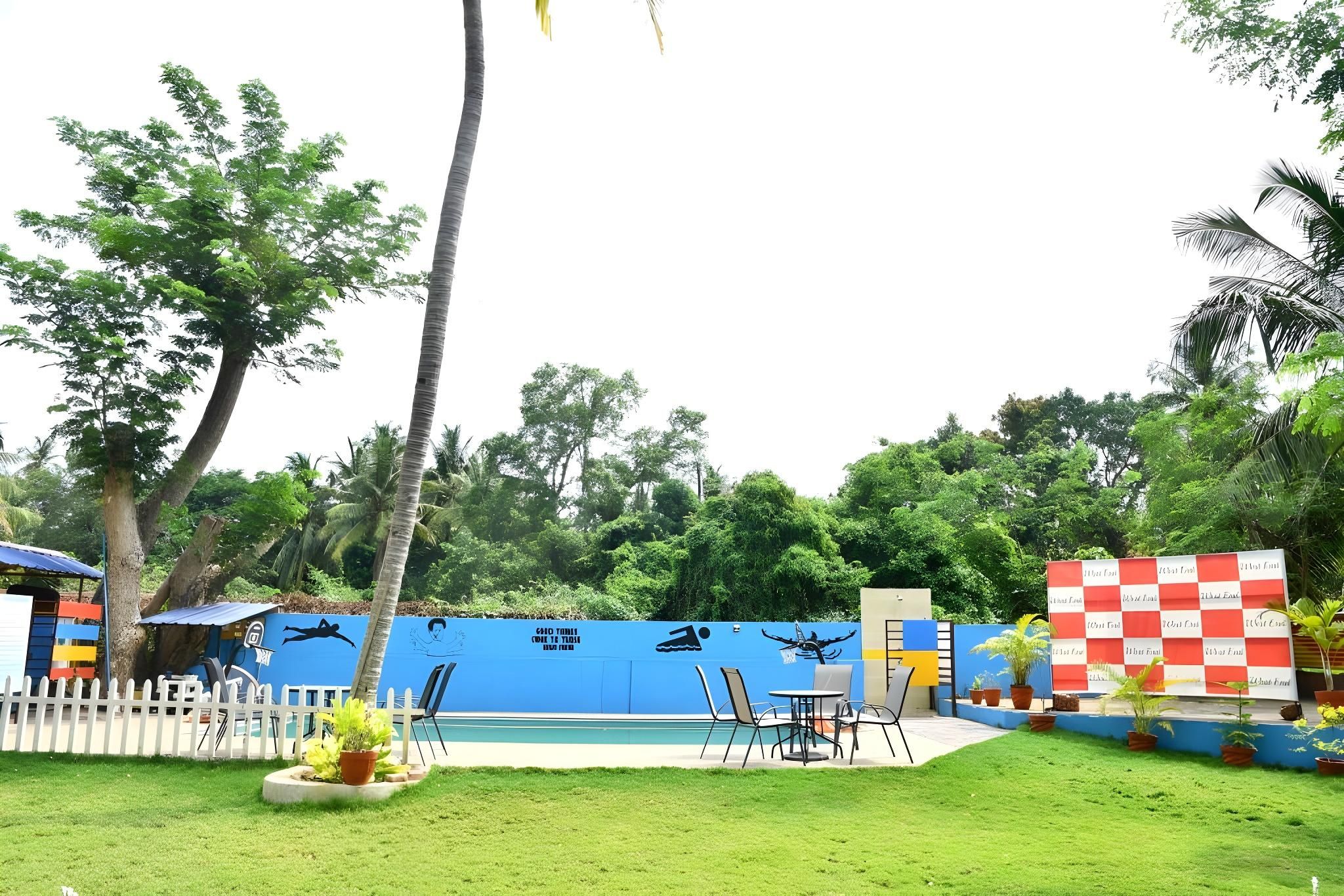 Ein Poolbereich mit blauer Wand, Stühlen und weißem Zaun.