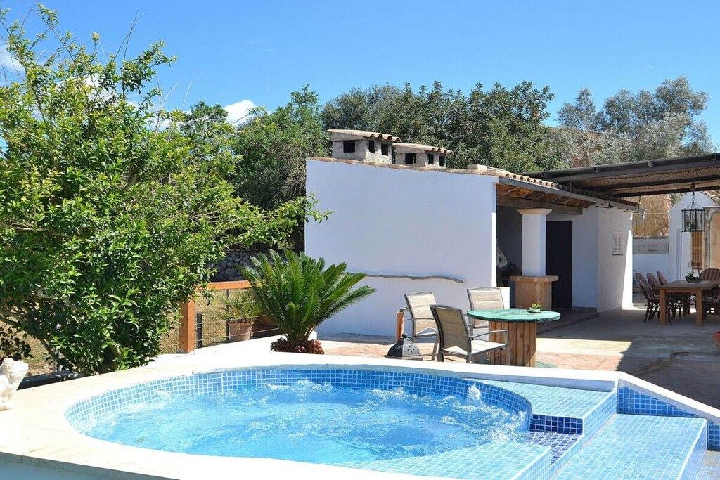Ein Swimmingpool mit einer weißen Wand und einer Pergola im Hintergrund.