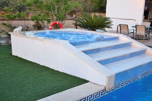 A hot tub with steps leading into it, surrounded by a small garden and outdoor furniture. - Finca in Muro with swimming pool (Muro)