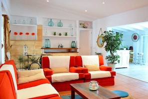 A modern living room with a sofa set, a coffee table, and a dining area with shelves and decorative items. - Finca in Muro with swimming pool (Muro)