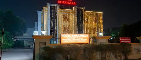 A hotel with illuminated signage, a well-lit entrance, and a paved driveway.